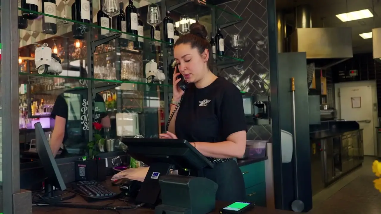 Servicemitarbeiterin am POS-Kassensystem im Flax Rankweil während eines Telefonats